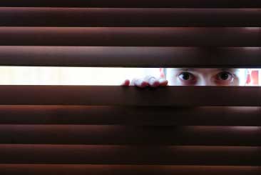 Man-lookingthroughblinds